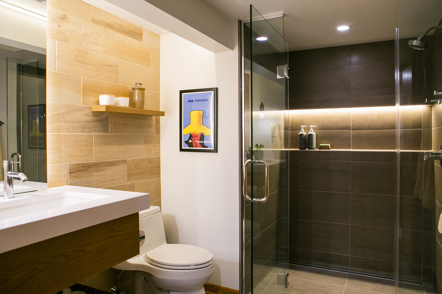 A full color image of a luxurious full bathroom with sink, toilet and tiled shower.